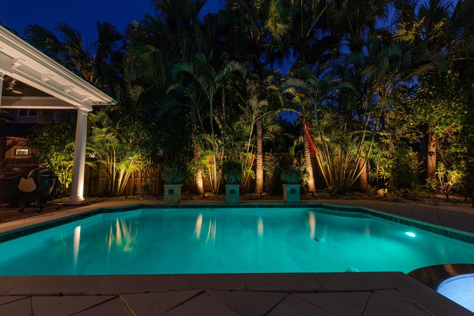 Pool and palm trees lit with landscape lighting at dusk